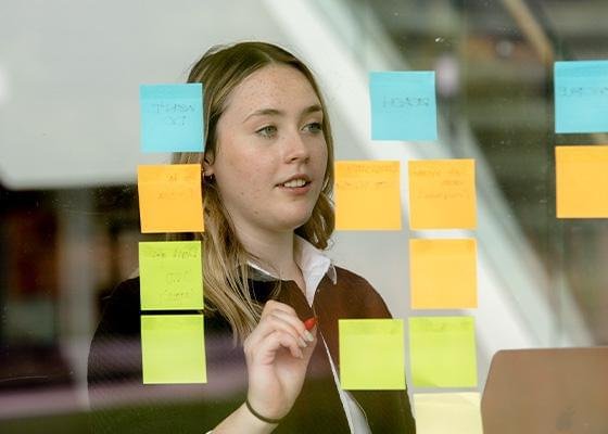 Photo of an intern working at a board with Postit notes