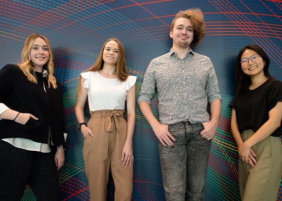 Photo of four college aged people in front of a CMU tartan themed wall