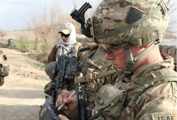 Photo of soldiers in fatigues in a rural environment