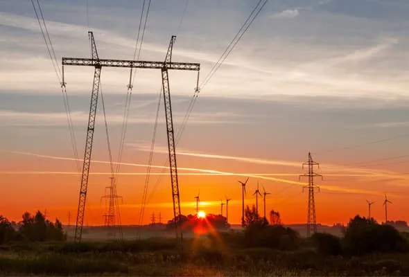 Photo of power lines and windmills at sunset